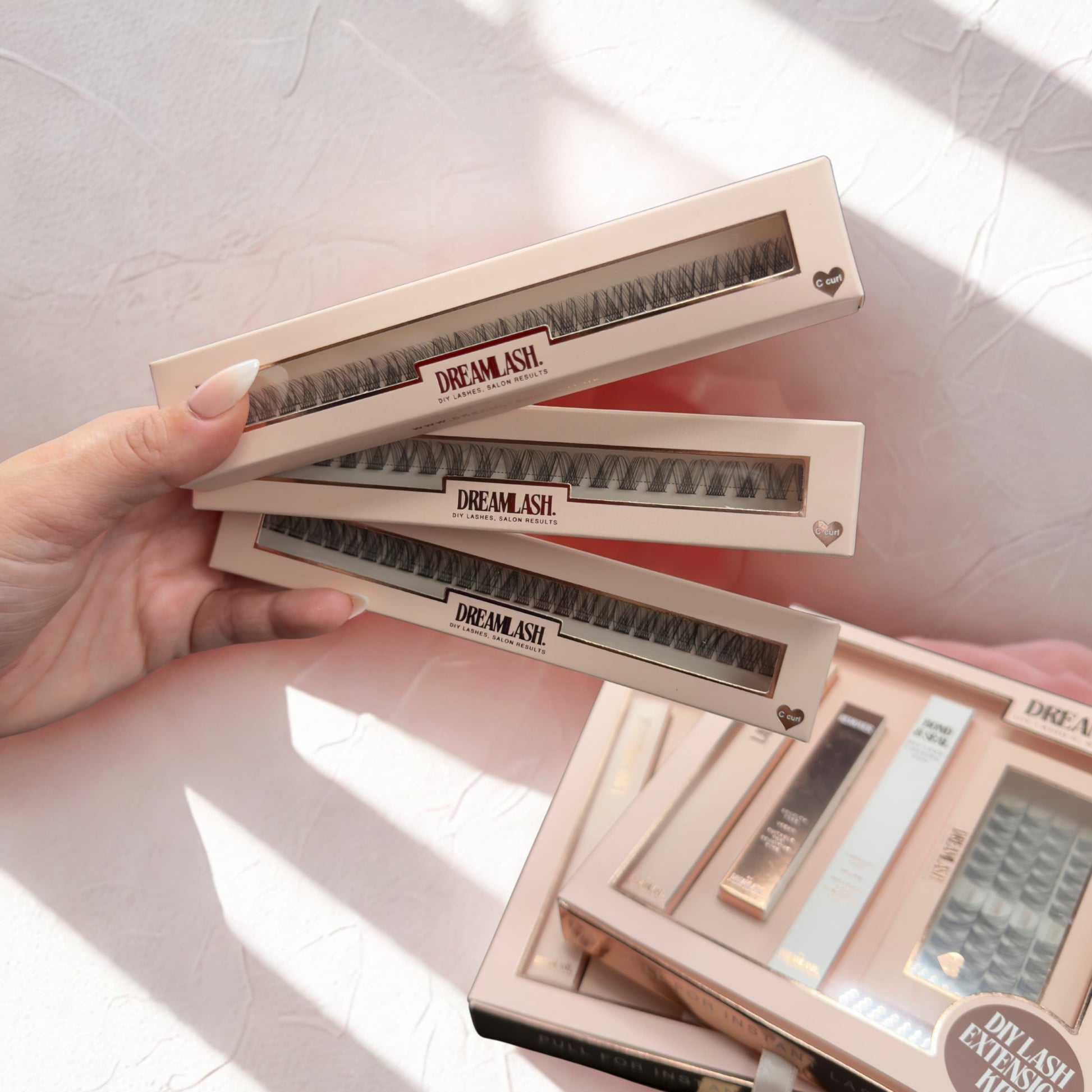Hand holding a set of Dreamlash eyelash extensions on a light background